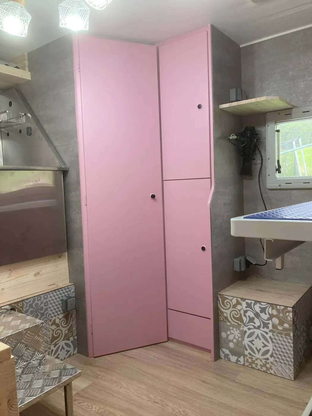 Armoire rose et rangements du salon de toilettage aménagé dans le camping-car